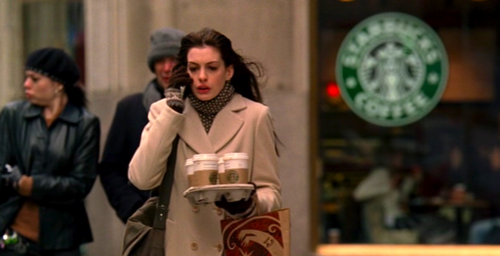 A cena é de "O Diabo veste Prada", mas é um retrato daqui também: café em uma mão e smartfone na outra.